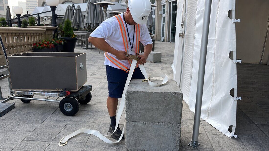 Installer securing a frame tent with concrete weights