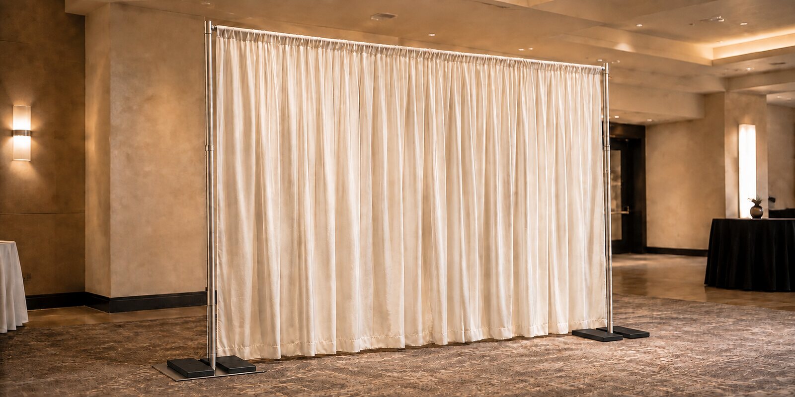 Freestanding pipe-and-drape backdrop with stainless steel uprights, white draping and rubber base weights