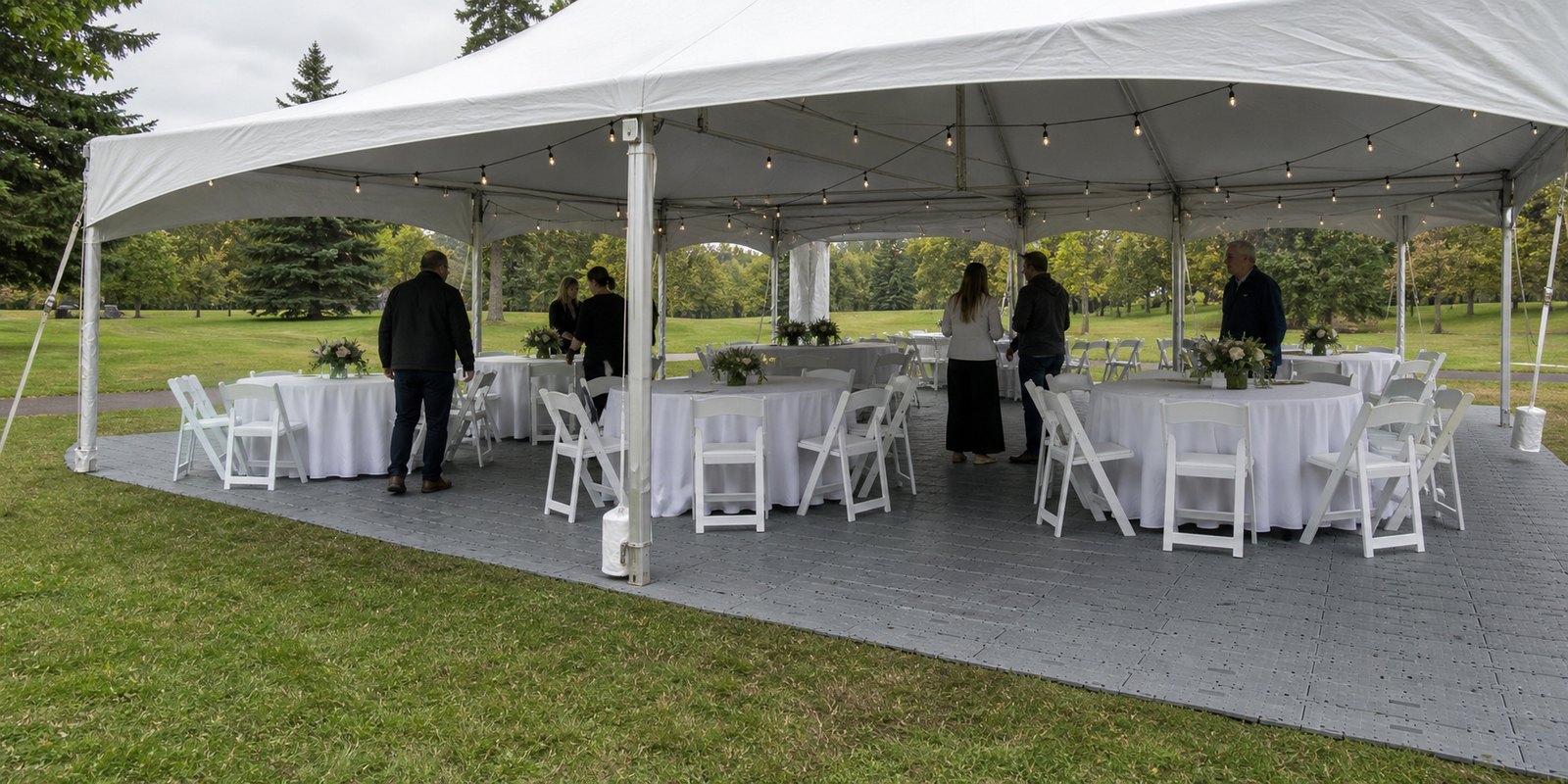 Temporary event flooring panels installed over grass beneath a white event tent